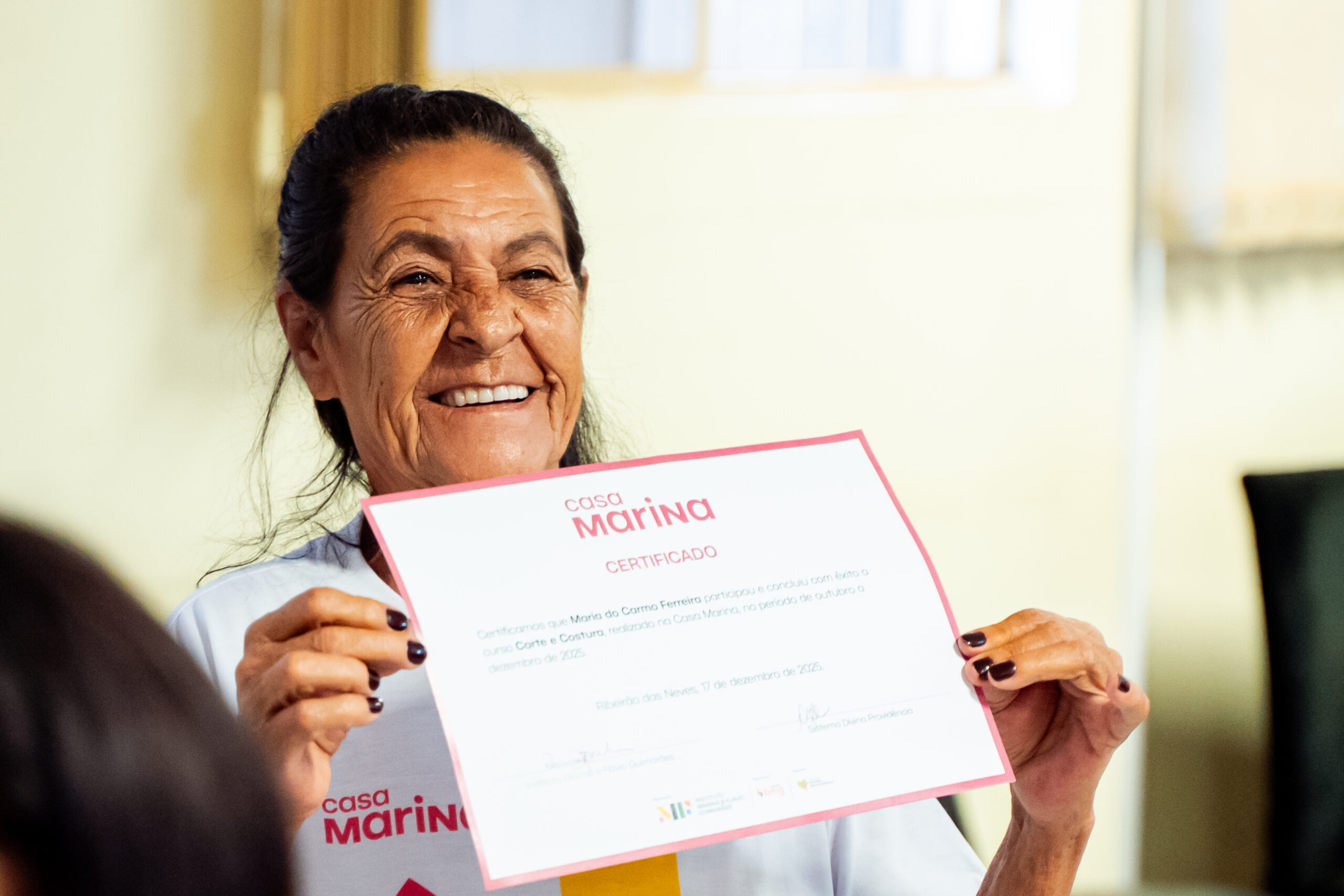 Aluna do projeto social casa marina sorrindo e segurando o diploma