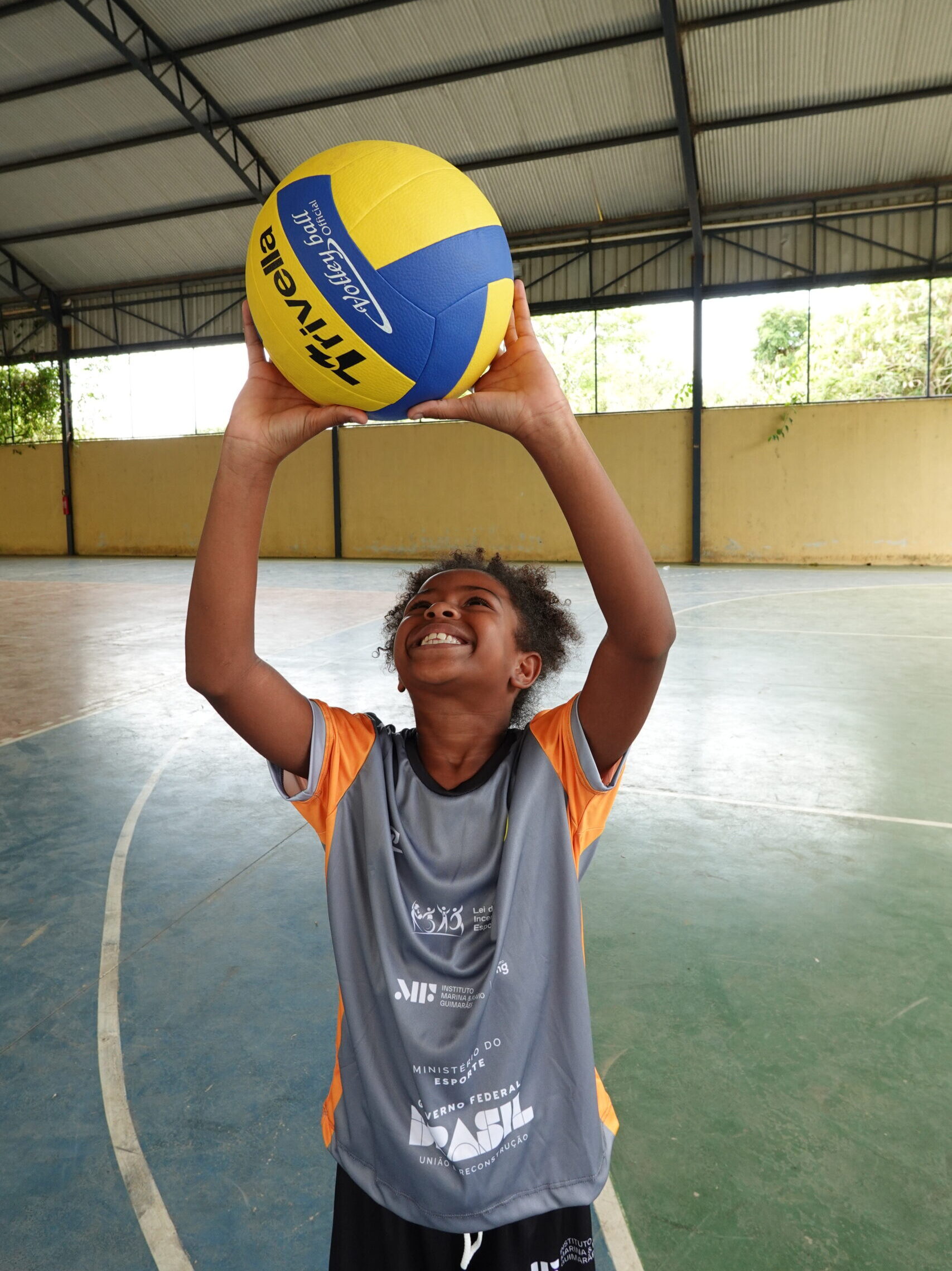 Aluna do projeto social Semear Esportes do Instituto Mais Ação jogando bola de vôlei para o alto