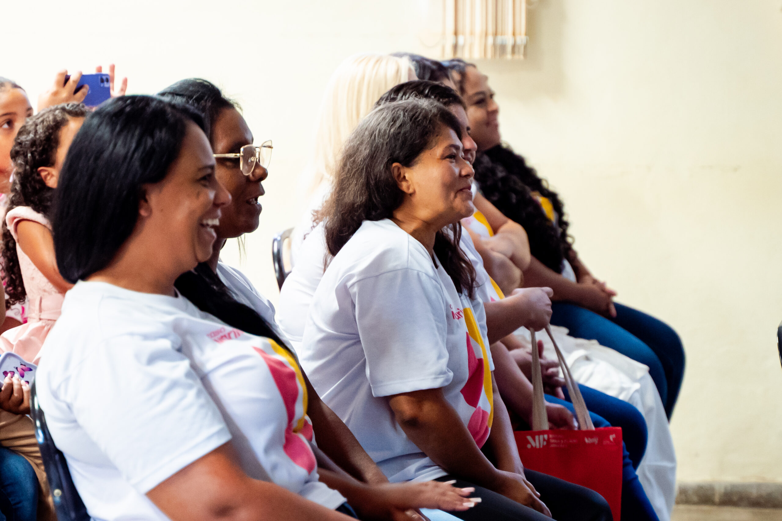 Alunas do projeto social casa marina sentadas em fila sorrindo