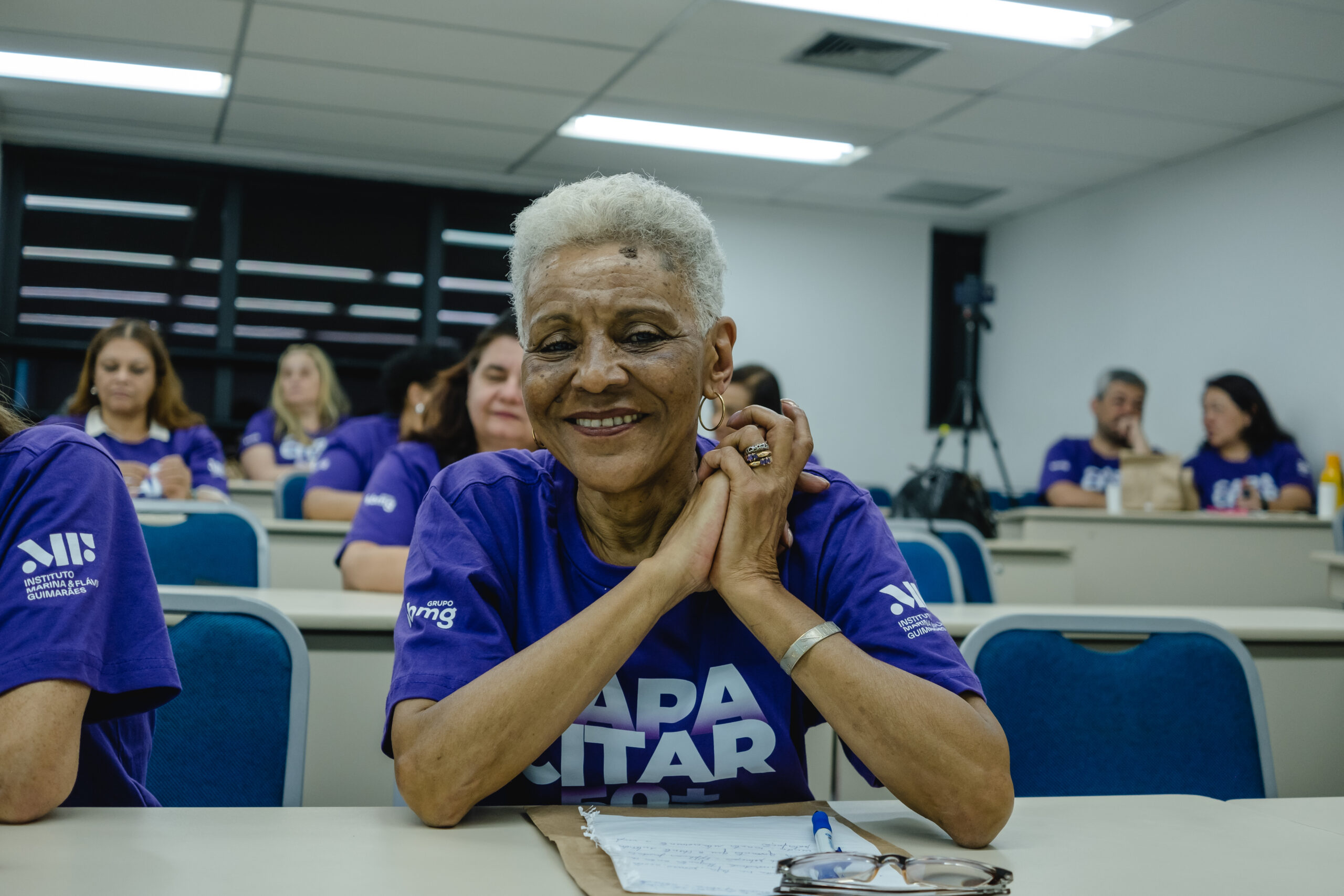 Aluna do projeto social Capacitar 50+ com os braços frente ao corpo sorrindo para a foto