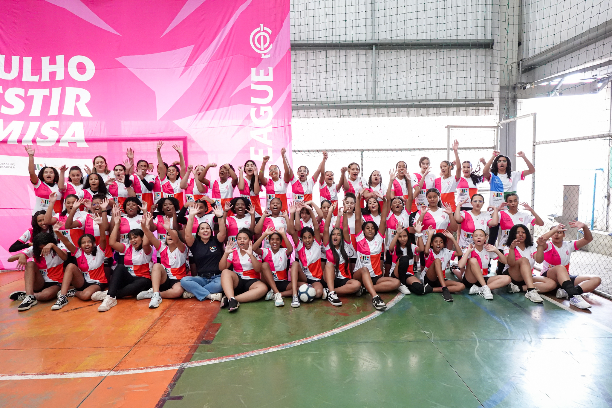 Turma animada do projeto social Co-League comemorando com os braços para cima