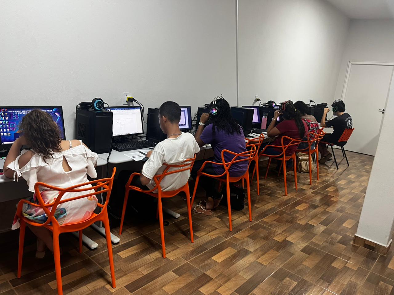 Alunos do projeto social Conectar Oportunidades dentro de sala de aula digitando no computador