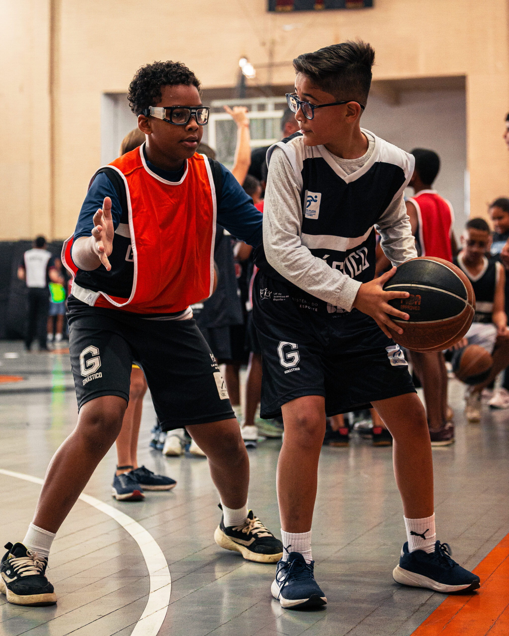 Crianças do projeto social Esporte Clube Ginástico jogando basquete em uma quadra