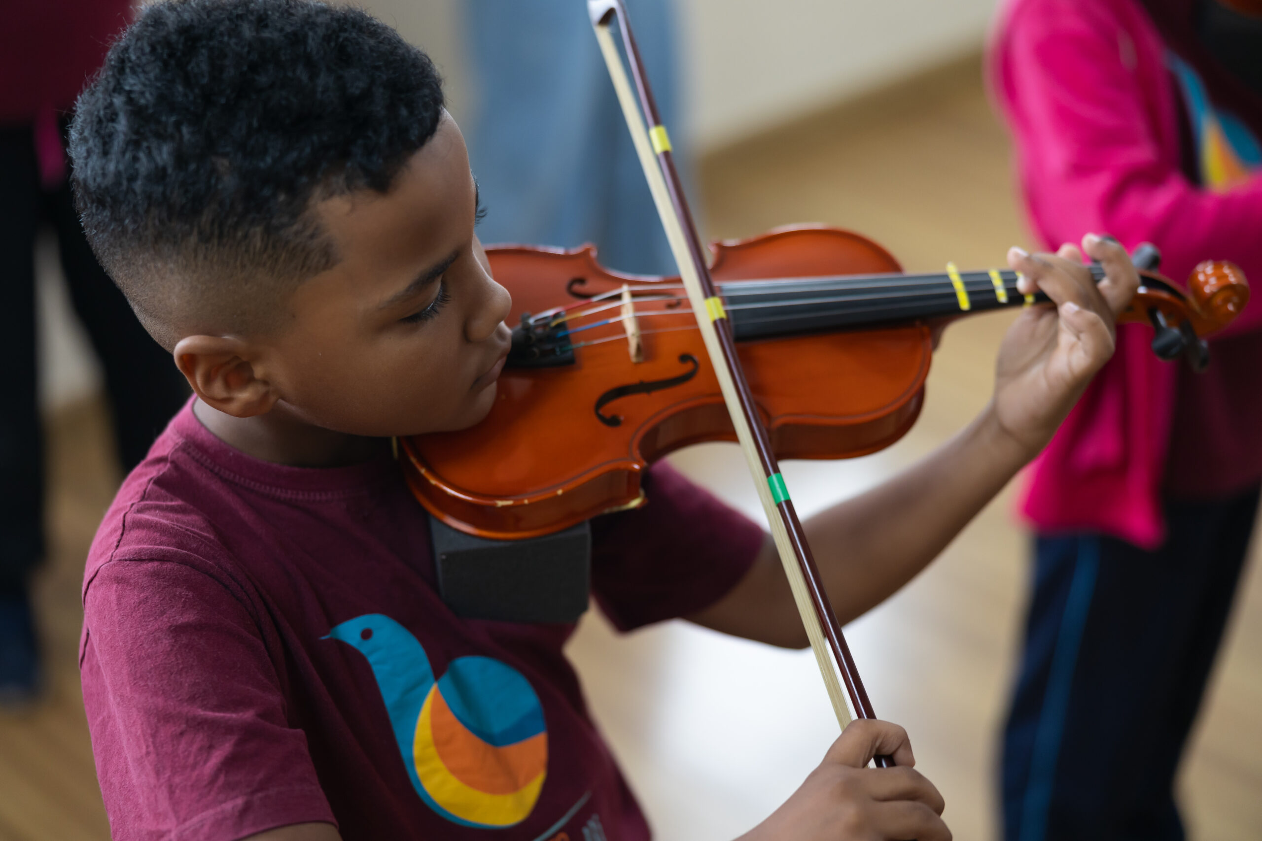 Aluno do projeto social do Instituto Baccarelli tocando atentamente o violino em suas mãos