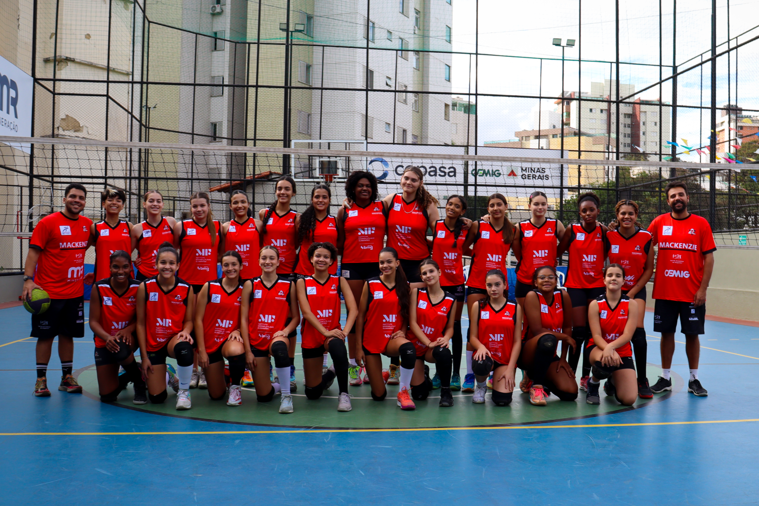 Alunas do projeto social Mackenzie reunidas e olhando para a foto após jogo de vôlei