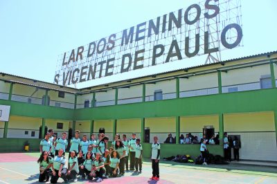 Estudantes do lar dos meninos são vicente de paulo no pátio a frente do letreiro com o nome da escola